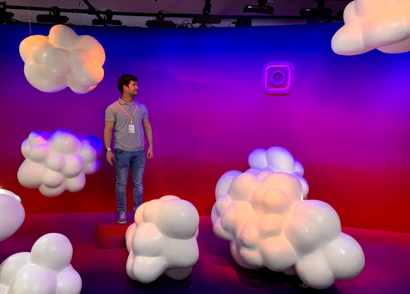 Matheus Siqueira standing among large white cloud sculptures, with the Instagram logo in neon on the wall.